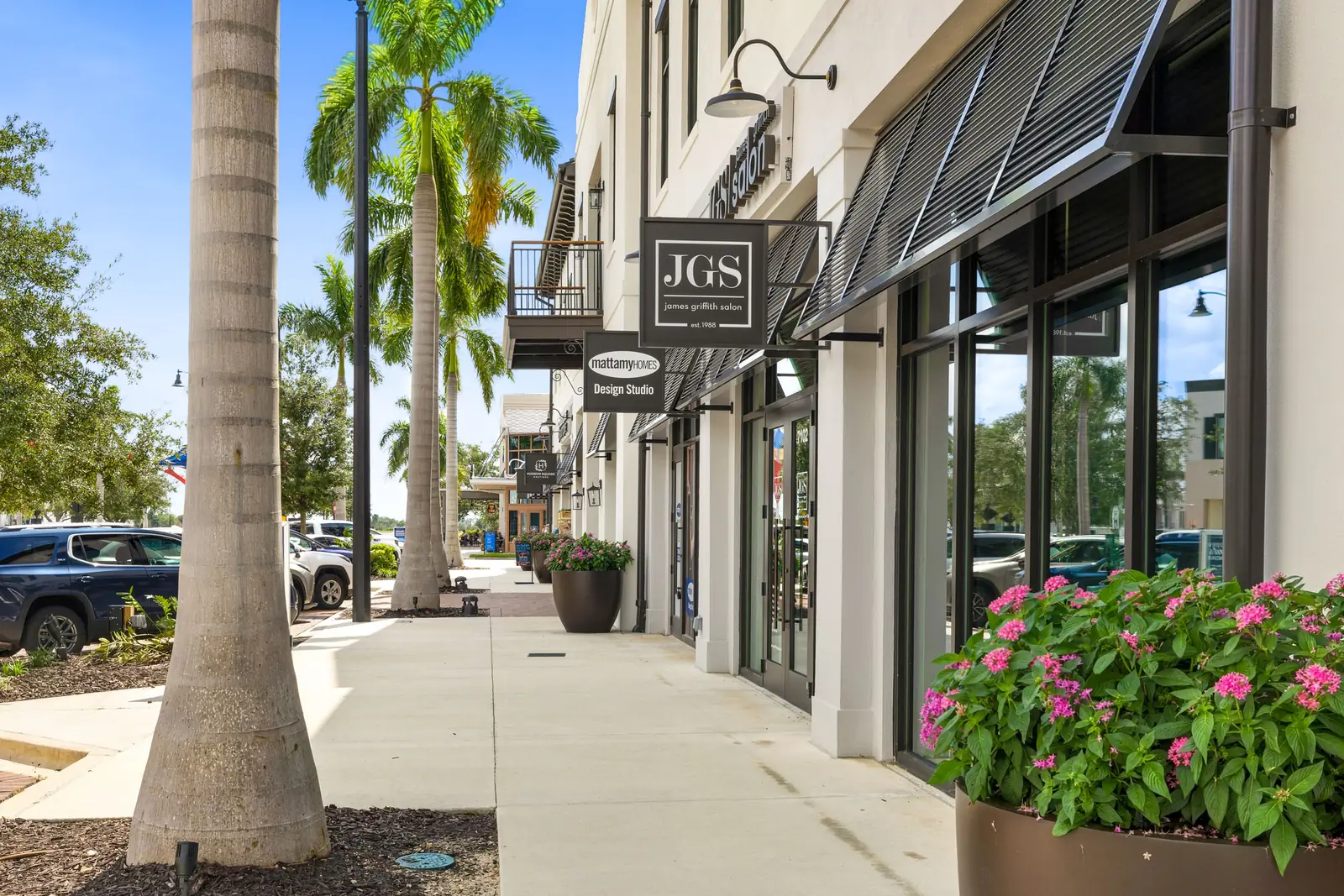 Shaded sidewalk lined with palms, planters and shop fronts in Downtown Wellen Park
